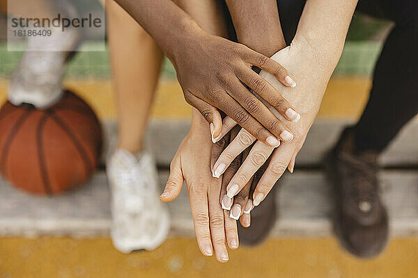 Multiracial friends stacking hands in sports court