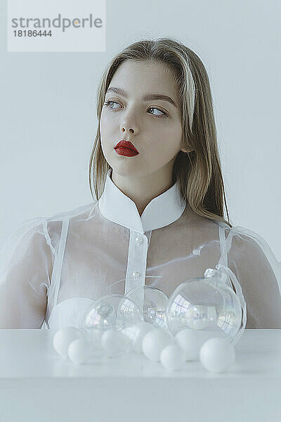 Thoughtful girl with red lipstick against white background