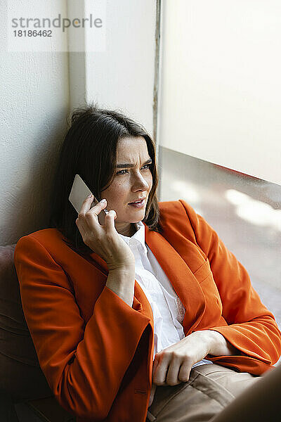 Businesswoman talking on mobile phone by window in office
