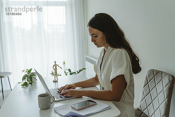 Geschäftsfrau benutzt Laptop am Tisch im Heimbüro