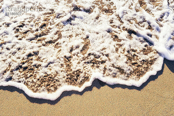Strandsand  gebürstet von schaumiger Welle