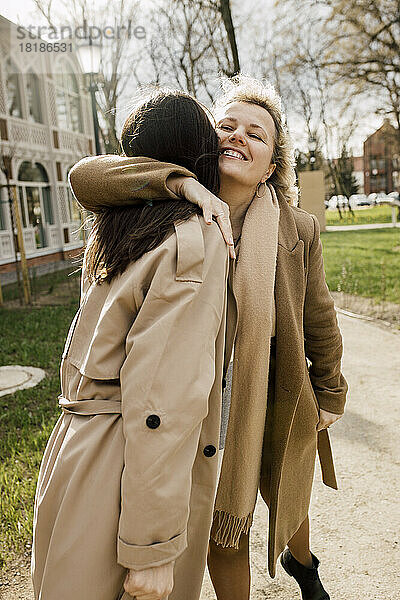 Smiling woman with arm around embracing daughter