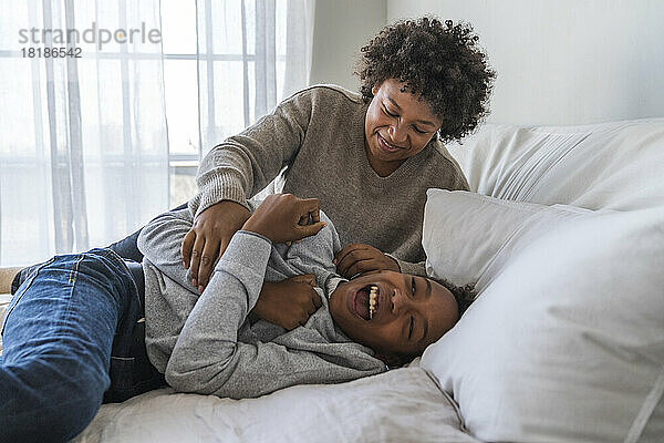 Verspielte Mutter tickt Sohn zu Hause im Bett