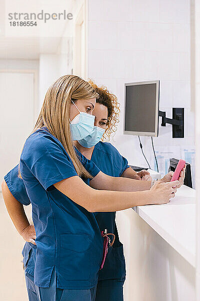 Ältere Krankenschwester und Kollegin nutzen Mobiltelefon im Krankenhaus