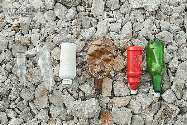 Leere Plastikflaschen auf Steinen am Strand