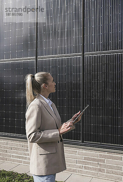 Junge Geschäftsfrau mit Tablet-PC untersucht Solarmodule