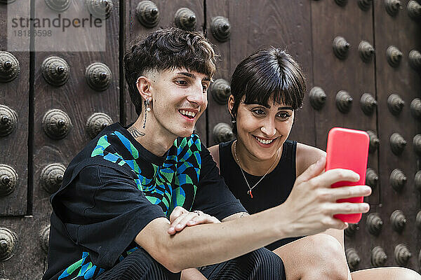 Glückliches junges Paar  das vor der Tür einen Videoanruf über das Smartphone führt