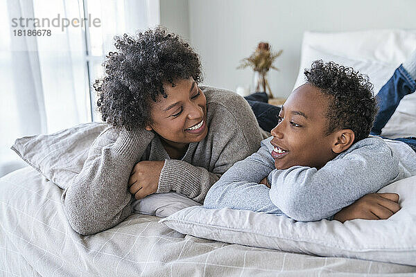 Glückliche Mutter und Sohn unterhalten sich zu Hause im Bett