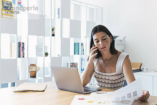 Junge Geschäftsfrau diskutiert Dokument auf Smartphone im Büro