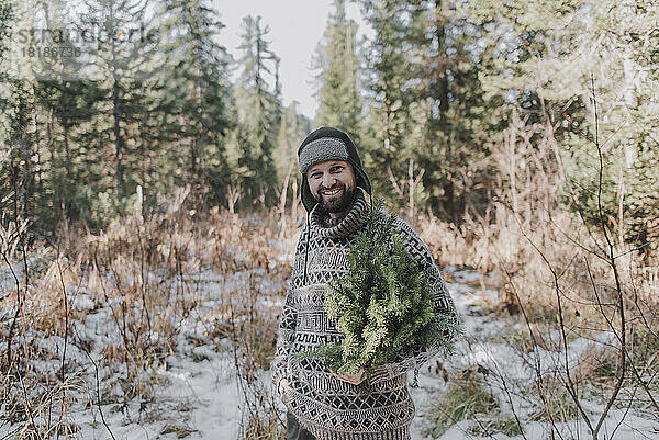 Lächelnder reifer Mann in warmer Kleidung im Wald