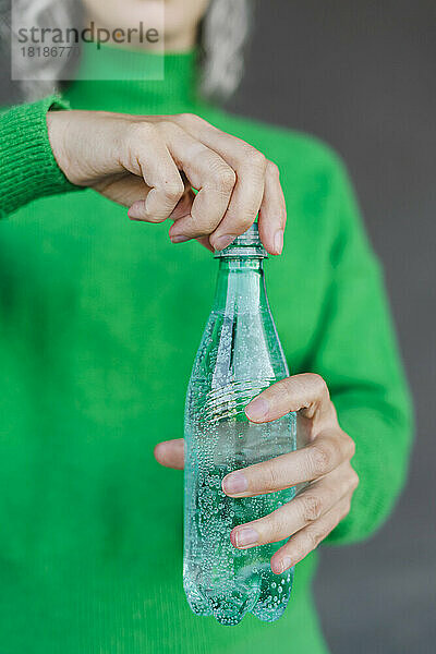 Frau öffnet Plastikwasserflasche