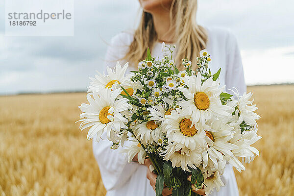 Frau hält Blumenstrauß im Feld