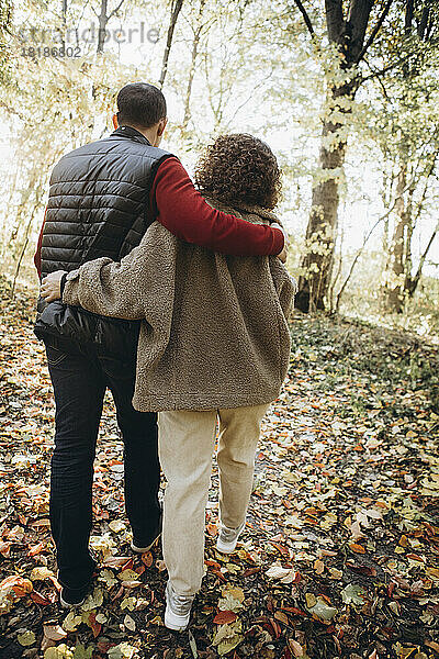 Paar mit Armen beim Spaziergang im Wald