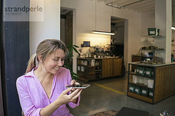 Glücklicher Freiberufler  der im Café mit dem Smartphone fotografiert