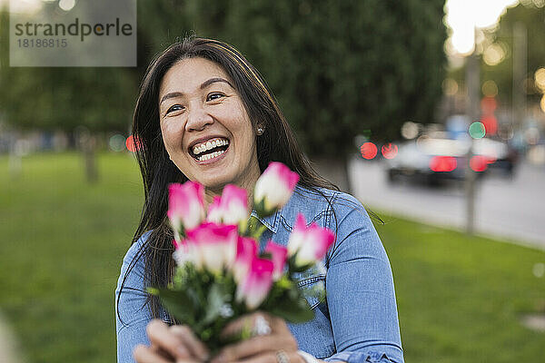 Glückliche reife Frau hält am Valentinstag Blumen im Park
