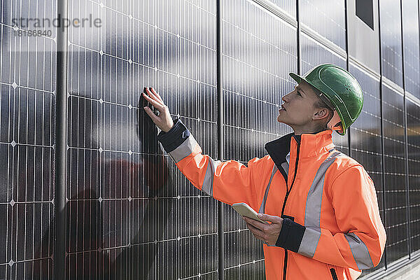 Junge Ingenieurin mit Smartphone untersucht Solarmodule