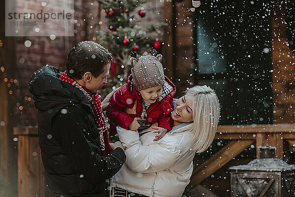 Fröhlicher Vater und Mutter spielen mit Sohn im Schnee