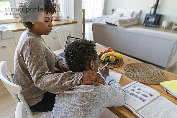 Mutter hilft Sohn beim Lernen am Tisch zu Hause
