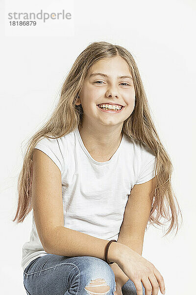 Smiling girl sitting against white background