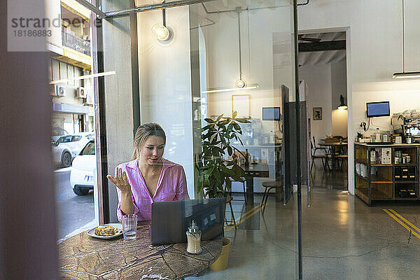 Freiberufler spricht per Videoanruf über Laptop im Café