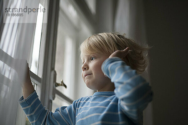 Little boy looking out of window waiting