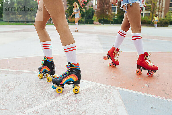 Frau mit Freunden beim Rollschuhlaufen auf dem Sportplatz