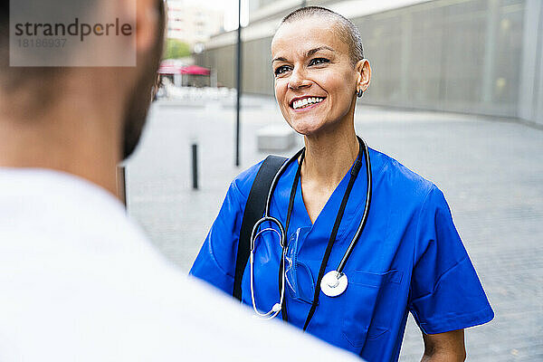 Lächelnde Krankenschwester mit Stethoskop im Gespräch mit Kollegen