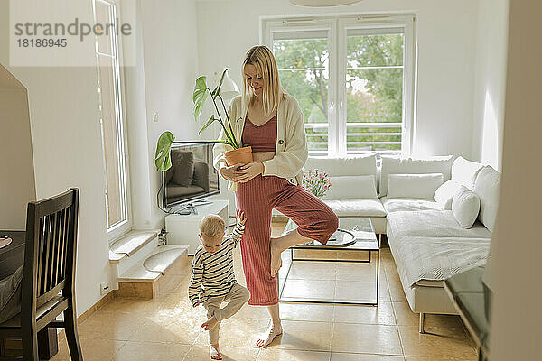 Junge mit Mutter hält Monstera-Pflanze im heimischen Wohnzimmer