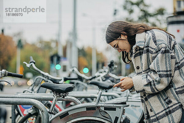 Junge Frau entriegelt Fahrrad per Smartphone