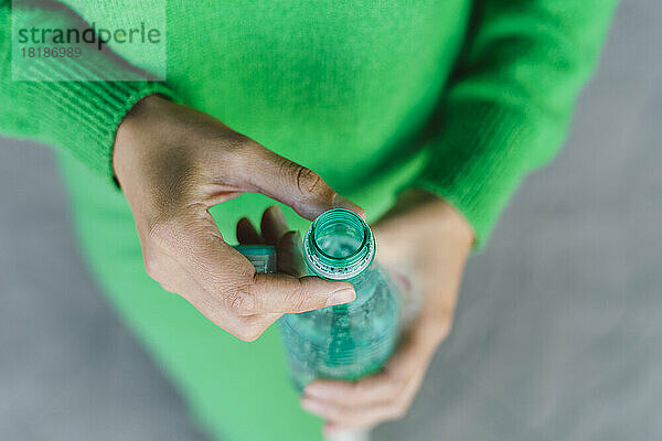 Frau hält grün geöffnete Plastikflasche