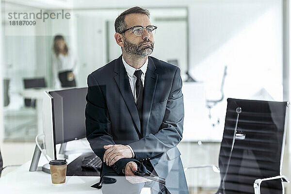 Nachdenklicher Geschäftsmann sitzt mit Tablet-PC im Büro