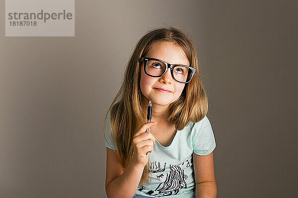 Portrait of smart girl with oversized glasses thinking