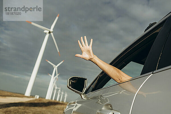 Hand einer Frau aus Autofenster im Windpark