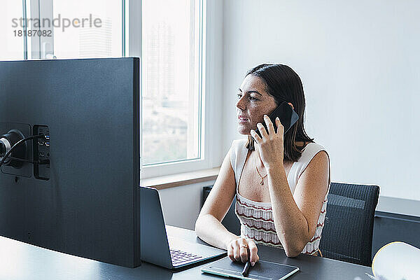 Junge Geschäftsfrau spricht im Büro per Smartphone