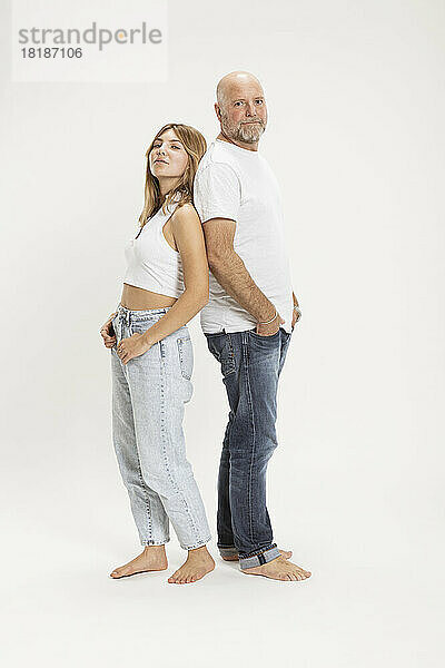 Confident father and daughter with hands in pockets at studio