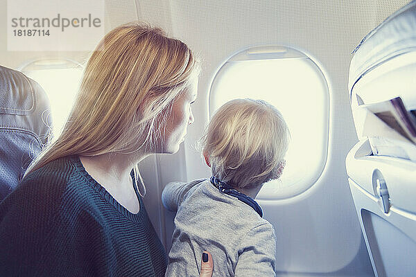 Mother with son in airplane looking out of window