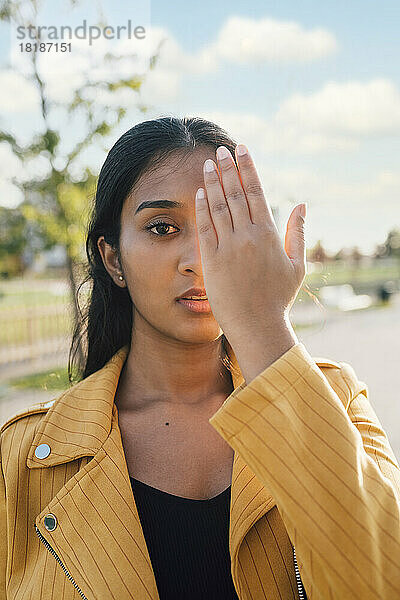 Frau bedeckt Gesicht mit Hand an sonnigem Tag