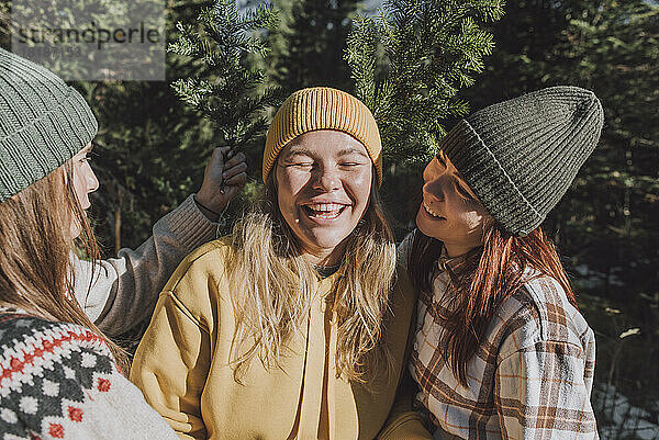 Glückliche Frauen mit einem Zweig eines immergrünen Baumes  der einen Freund im Wald anschaut