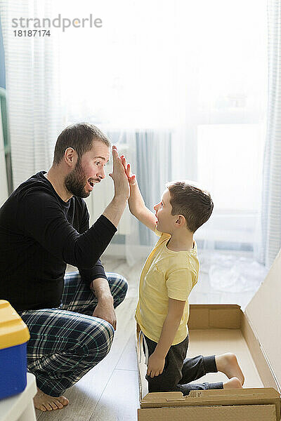 Vater gibt seinem Sohn in der Kiste zu Hause High-Five