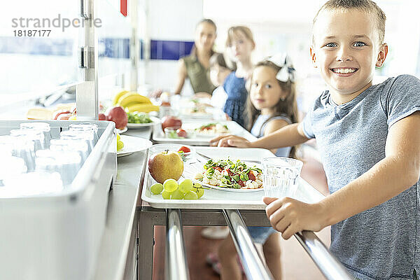 Fröhlicher Schüler mit gesunder Mahlzeit in der Mittagspause
