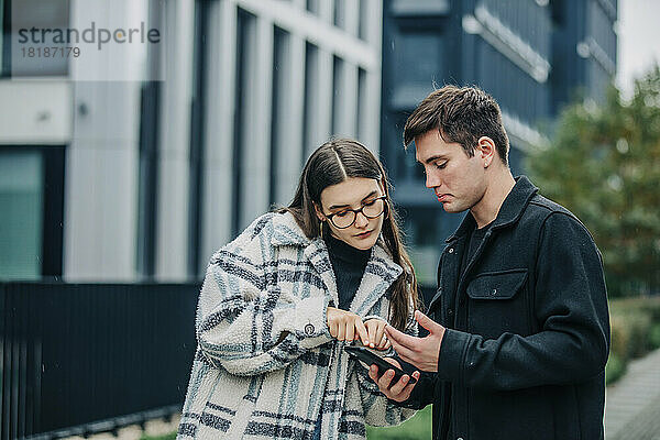 Junger Mann und Frau telefonieren auf der Straße über ihr Mobiltelefon