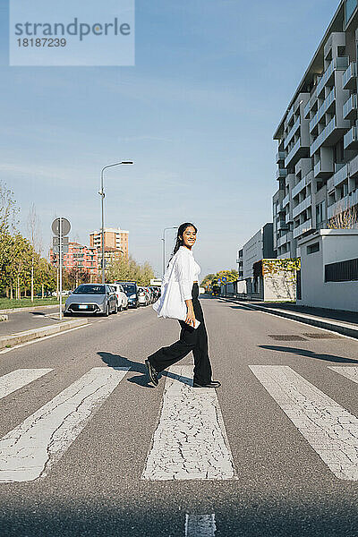 Junge Frau überquert an einem sonnigen Tag die Straße