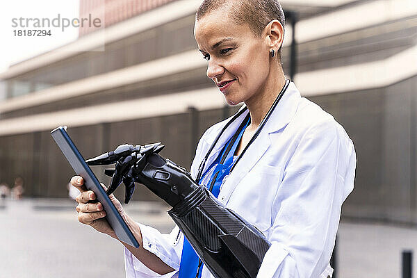 Lächelnde Ärztin mit künstlichem Glied mittels Tablet-PC