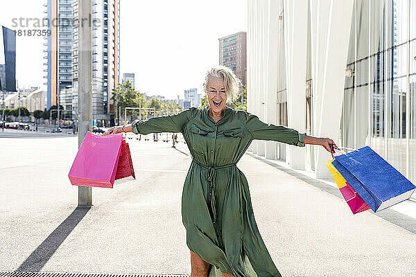 Glückliche Frau  die an einem sonnigen Tag Einkaufstüten trägt