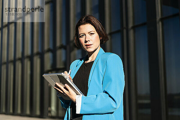 Selbstbewusste Geschäftsfrau mit Tablet-PC an einem sonnigen Tag