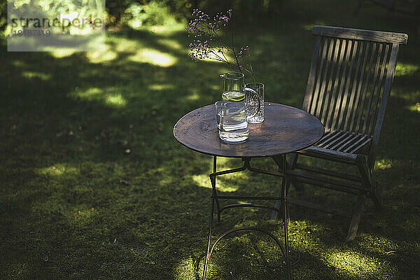 Table and chair with water jug in garden