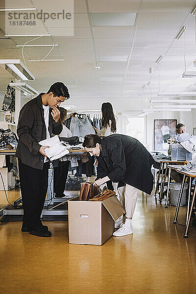 Männlicher und weiblicher Modedesigner beim Auspacken eines Kartons in einer Werkstatt