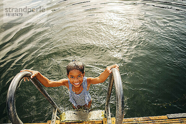 Hohe Winkel Ansicht des lächelnden Mädchen hält Geländer  während in der Nähe von Schritten in See stehen