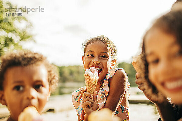 Glückliches Mädchen isst Eis mit Familie im Urlaub