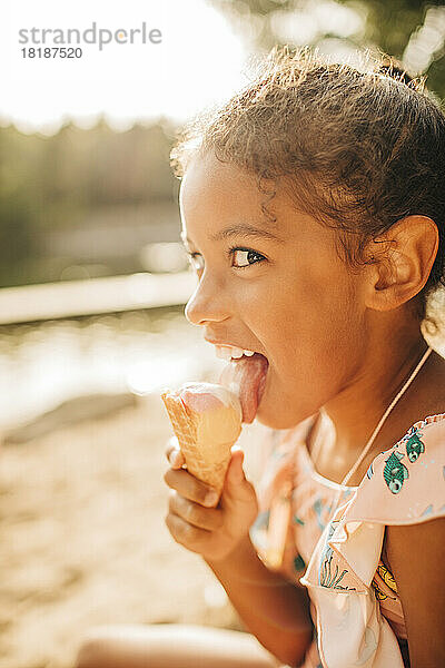 Mädchen schaut seitwärts  während sie an einem sonnigen Tag Eis leckt